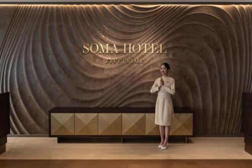 a woman in a dress standing in front of a wall at SOMA HOTEL Riverside in Phnom Penh
