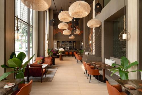 a restaurant with tables and chairs and pendant lights at SOMA HOTEL Riverside in Phnom Penh