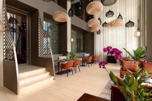 a dining room with chairs and tables and pendant lights at SOMA HOTEL Riverside in Phnom Penh