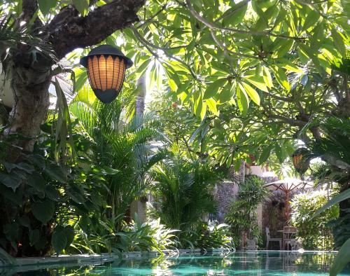 a light hanging from a tree next to a swimming pool at Uma Karan in Seminyak