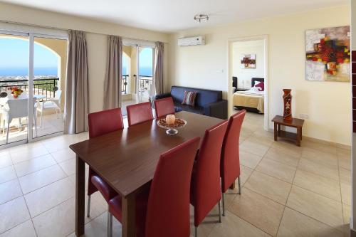 a dining room with a table and chairs and a living room at Club St. George in Paphos City