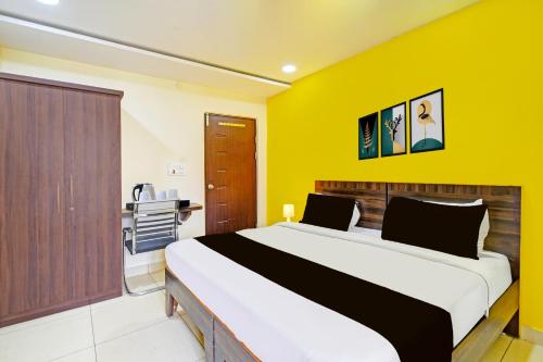 a bedroom with a large bed with a yellow wall at Super Hotel O Kondapur Hyderabad Formerly Dunes Inn in Hyderabad