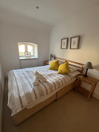 a bedroom with a large bed with two yellow pillows at Cosy Cottage Overlooking Malmesbury Abbey in Malmesbury