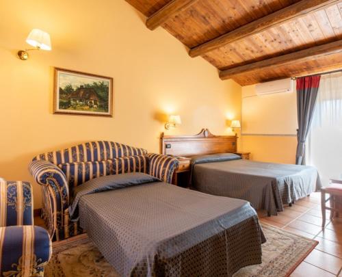 a living room with two chairs and a couch and a bed at Hotel Il Barocco in Ragusa