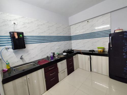 a kitchen with a sink and a black refrigerator at P S rahatani in Chinchiwad