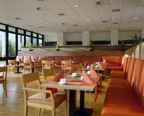 a dining room with tables and chairs in a restaurant at Overnight Tagungshotel im ABZ in Kerpen
