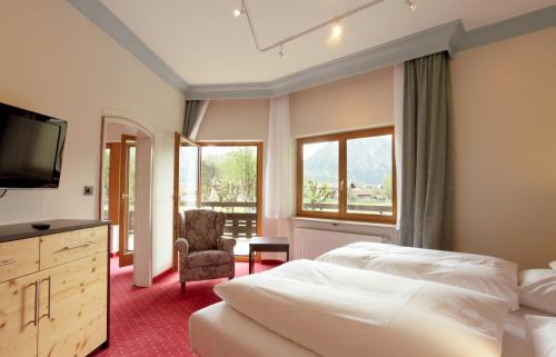 a bedroom with a bed and a tv and a chair at Wittelsbacher Hof in Oberstdorf