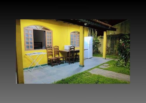 a yellow house with a table and chairs at Pousada Canto de Bertioga in Bertioga