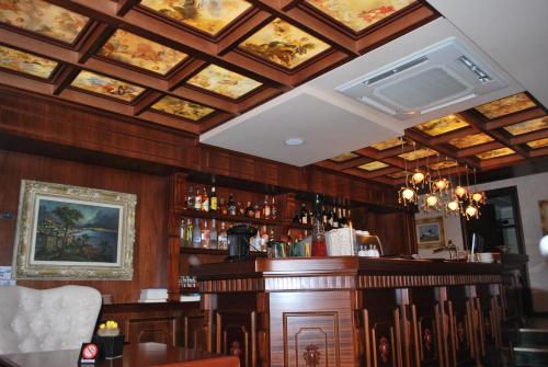 un bar con paredes de madera y techos con pinturas en Hotel Vila Sigal Korce, en Korçë