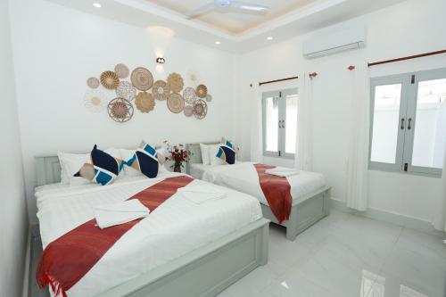 ルアンパバーンにあるCozy Inn Boutique Luangprabang Laosの白い壁と窓が特徴のベッドルーム1室(ベッド2台付)