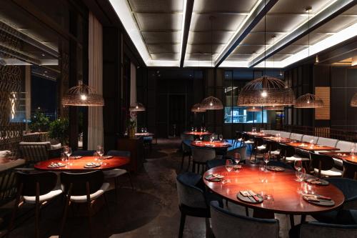 a dining room with tables and chairs and chandeliers at SOMA HOTEL Riverside in Phnom Penh