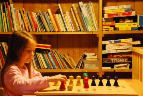 a young girl playing chess in a library at Bio Ferienbauernhof Greber in Schwarzenberg im Bregenzerwald