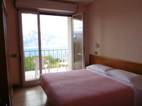 a bedroom with a bed with a view of a balcony at Hotel Miralago in San Zeno di Montagna