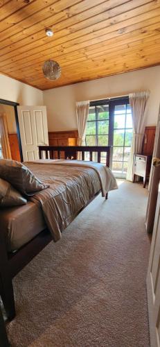 una camera da letto con un letto grande e un soffitto in legno di Shiprock Farm Cottage 