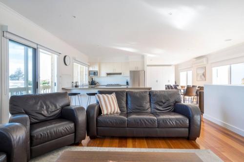 a living room with two leather couches and a kitchen at Sea Quinn Escape - Steps to Dromana Beach and Dining in Dromana