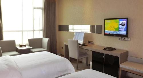 a hotel room with a bed and a desk with a television at GreenTree Alliance Shenzhen Shekou Sea World Hotel in Shenzhen