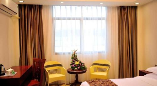 a hotel room with yellow chairs and a table and a window at Jian Guo Grand Hotel in Vientiane
