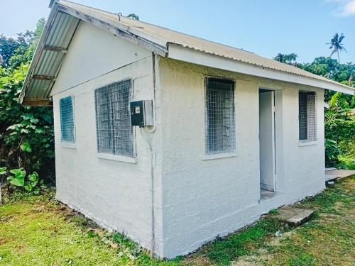 a small white house with a door and windows at Niu Cottage - Entire Place in Nuku‘alofa
