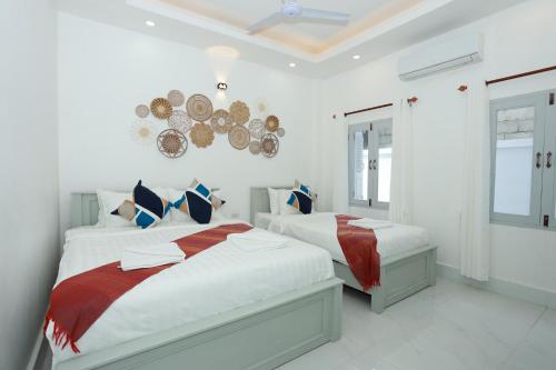 Un dormitorio blanco con dos camas y un espejo. en Cozy Inn Boutique Luangprabang Laos, en Luang Prabang