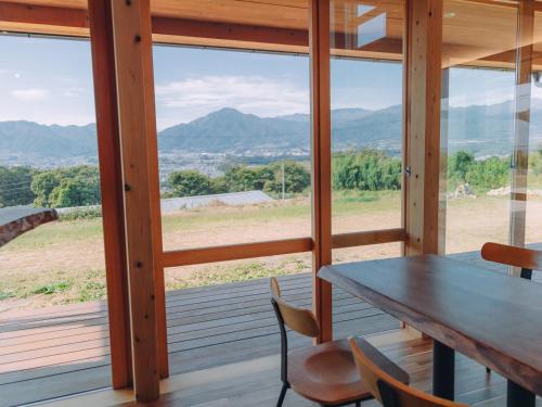 a dining room with a table and chairs and mountains at Cider Barn &more in Iida