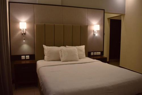 a bedroom with a large bed with white pillows at Sunset Suites in Karachi