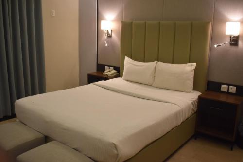 a large bed in a hotel room with two lamps at Sunset Suites in Karachi