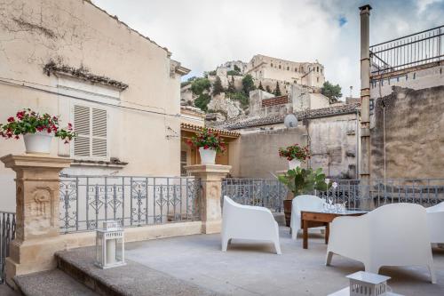 a patio with white chairs and a table and a building at Palazzo Montalbano in Scicli