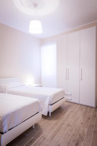 a white bedroom with two beds and a cabinet at Palazzo Montalbano in Scicli