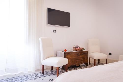 a bedroom with two chairs and a tv on the wall at Palazzo Montalbano in Scicli