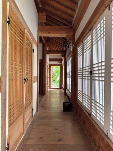 an empty hallway of a house with wooden floors and windows at Korean Traditional House - Chungnokdang in Boseong