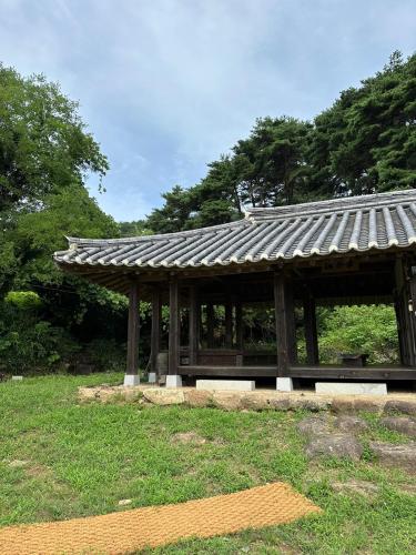 a wooden pavilion with a roof in a park at Korean Traditional House - Chungnokdang in Boseong