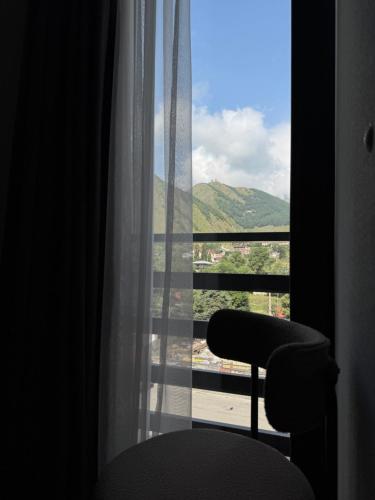 a window with a chair and a view of a city at Hotel Daba Kazbegi in Stepantsminda