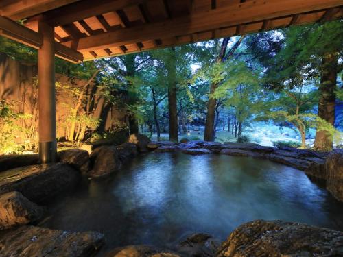 佐賀市にあるSaga Fugaの橋の下の岩と木々のある池