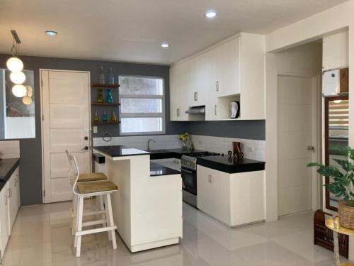 a kitchen with white cabinets and a stool in it at House at the City Center in Tuguegarao City