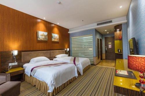 a hotel room with two beds and a couch at Harmony Resort Hotel Zhuhai in Zhuhai
