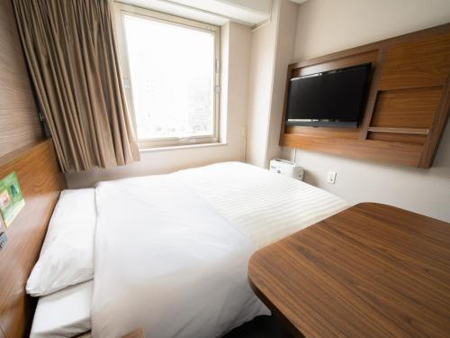 a bedroom with a large white bed with a flat screen tv at Natural Hot Spring SUPER HOTEL Kumamoto Chamber of Commerce in Kumamoto