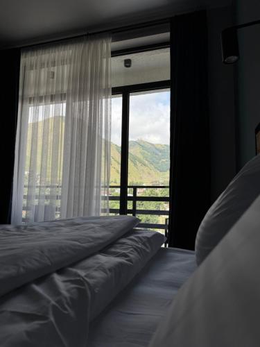 a bedroom with a bed and a large window at Hotel Daba Kazbegi in Stepantsminda