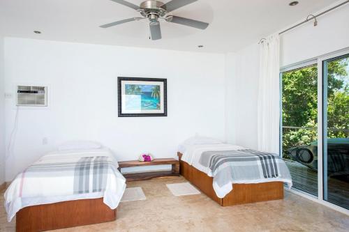 two beds in a room with a window at Touch of Class Villa - A Caribbean Beachfront Home villa in Savannah Sound