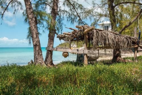 a hut on the beach next to the ocean at Touch of Class Villa - A Caribbean Beachfront Home villa in Savannah Sound