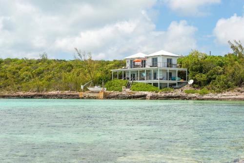 a house on the shore of a body of water at Touch of Class Villa - A Caribbean Beachfront Home villa in Savannah Sound