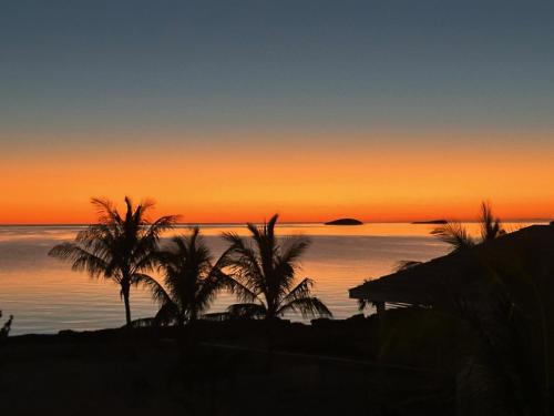 a sunset over the ocean with palm trees in the foreground at SeaEsta - Brand New Estate withPool & Private Backyard Beach home in South Palmetto Point