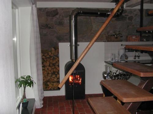 a stove in a kitchen with a pile of logs at Apan & Klyset in Simrishamn