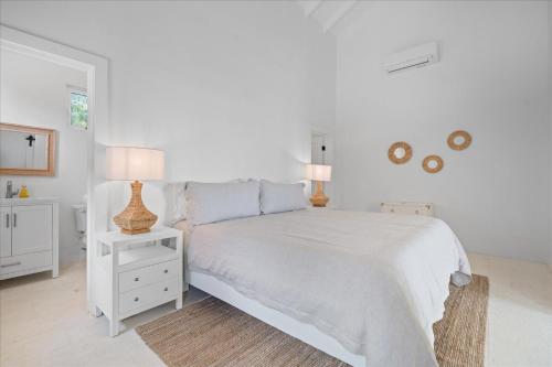 a white bedroom with a white bed and two lamps at SeaEsta - Brand New Estate withPool & Private Backyard Beach home in South Palmetto Point