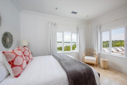 a white bedroom with a bed and two windows at Turtle Pointe - Lux New Windermere Home withPool, Boat Dock, Beach home in Savannah Sound