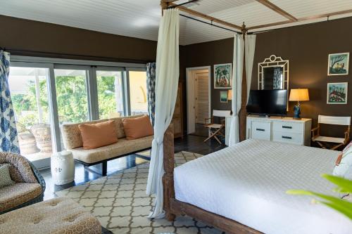 a bedroom with a bed and a couch and a television at Beehive Harbour Island, Luxury Dream World on the Bay, Private d home in Harbour Island
