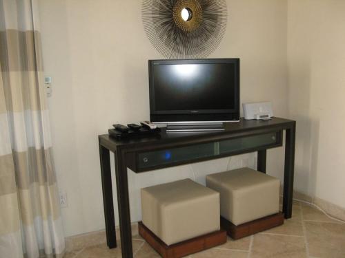 a television sitting on a table with two stools at Sky Beach Club Bungalow 3 Steps from Beach With Club, Pool bungalow in Colebrooke Dale