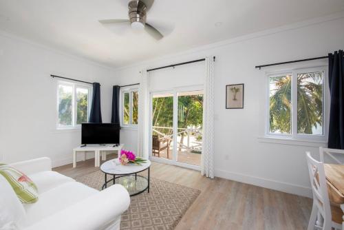 a living room with a white couch and windows at Laughing Bird 1BR #2 - Brand New Stylish Apartment, Pool, Beach condo in Colebrooke Dale