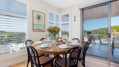 a dining room with a table and chairs and a balcony at Summit to Sea in Kiama