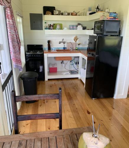 a kitchen with a black refrigerator and a wooden floor at Cayo Loco Studio - Cayo Loco Pink Sand Beachview Studio Villa home in Colebrooke Dale
