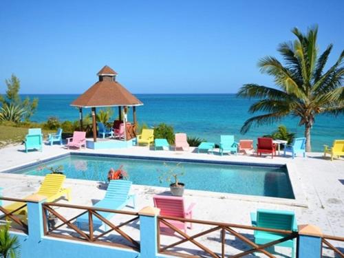a pool with chairs and a gazebo and the ocean at On the Dune - Beachfront Cottage with 50 Mile Ocean View, Pool villa in Palmetto Point